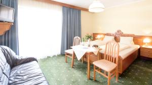 ein Hotelzimmer mit einem Bett, einem Tisch und Stühlen in der Unterkunft Parkhotel Zuzek in Sankt Kanzian am Klopeiner See