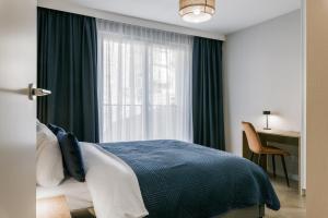 a bedroom with a bed and a window and a desk at Metropolis Design Apartments in Kraków