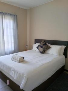 a bedroom with a bed with white sheets and a window at ReMo in Sandton +4 photos