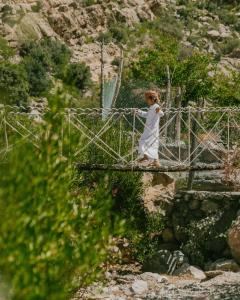 a woman standing on a bridge over a river at the suwgra-Al-Jabal Al-Akdar in Sūkirah