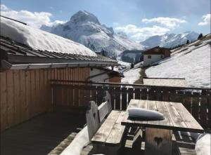 a wooden table on a balcony with snow covered mountains at Appartement Kriegerhorn in Lech am Arlberg +7 photos