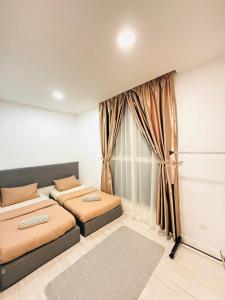 two beds in a room with a window at The Anggun Sutera Avenue in Kota Kinabalu