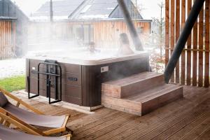 a couple in a hot tub on a deck at Chalet Wellness TRI VODY Demänovská Dolina in Liptovský Mikuláš