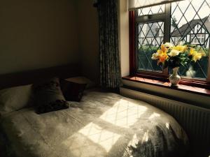 a bedroom with a bed and a vase of flowers in a window at Edgware B&B in Barnet