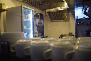 a bunch of cups in a kitchen with a refrigerator at Hotel Deluxe in Rānchī