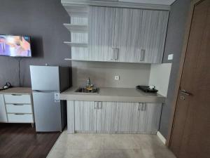 a kitchen with a sink and a white refrigerator at Apt Puri Orchard Lani's Transit in Jakarta