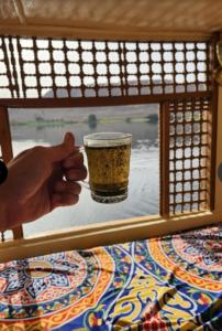 a person holding a glass in front of a window at Nile Bride Felucca in Aswan