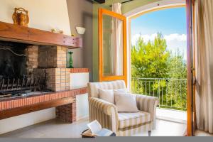 a living room with a fireplace and a chair and a window at La Belle Villa - Family Retreat Magnificent View in Akrotiri +34 photos
