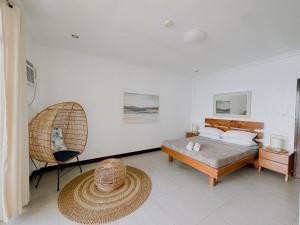 a bedroom with a bed and a chair at Wuthering Heights Bed & Breakfast by the Sea in Dumaguete