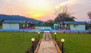 un sentiero che conduce a una casa con un tramonto sullo sfondo di Publiq Darbar Tent House a Pune