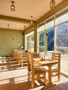 ein Restaurant mit Holztischen und -stühlen und Fenstern in der Unterkunft Cafe Alpenglow in Sissu