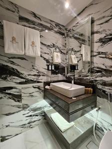 a bathroom with a sink and a marble wall at Royal Plaza Hotel in Duqm