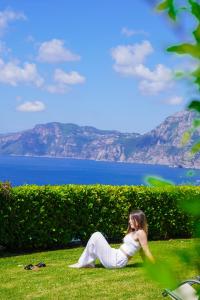 a woman sitting on the grass talking on a cell phone at Masa Villas in Praiano