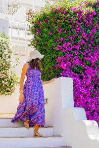 a woman in a dress walking down the stairs in front of flowers at Masa Villas in Praiano