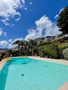 a large blue swimming pool with mountains in the background at Masa Villas in Praiano +14 photos