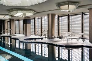 a pool in a building with chairs and a table at Excelsior Hotel Gallia, a Luxury Collection Hotel, Milan in Milan