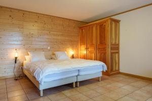 a bedroom with a bed and a wooden wall at Chalet La Rayée - Vue lac et montagne 14p in Gérardmer