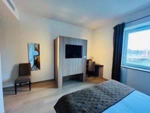 una camera da letto con un letto e una TV a schermo piatto di Au Moulin des Ecorces a Dole