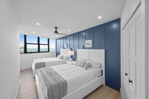 a bedroom with two beds and a blue wall at Beachfront condo with views of beach and spacious pool in Marco Island +26 photos