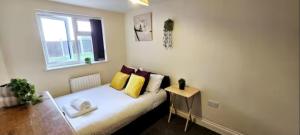 a bedroom with a bed with yellow pillows and a window at Arnstone Spacious 6 bedroom home with parking in Hythe