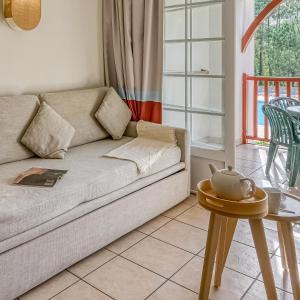 ein Wohnzimmer mit einer Couch und einem Tisch in der Unterkunft Résidence Pierre & Vacances Le Domaine de Gascogne in Biscarrosse