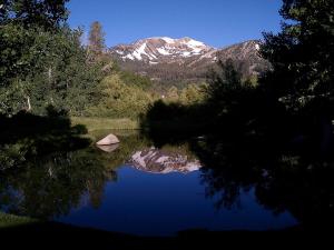 een weerspiegeling van een boot in een meer met een berg bij Snowcreek Resort Vacation Rentals in Mammoth Lakes