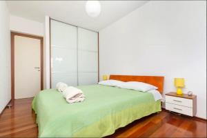 sypialnia z zielonym łóżkiem i 2 ręcznikami w obiekcie Apartment Put Meja w Splicie
