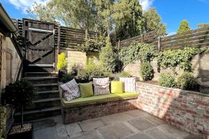 eine grüne Bank mit Kissen auf einer Ziegelmauer in der Unterkunft Stunning Town House in City Centre- Free Parking! in Bath