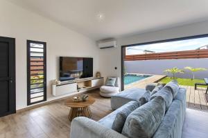 a living room with a large couch and a television at VILLA BELLEVUE classée 5 Etoiles - 4 chambres - piscine chauffée proche de l'aéroport et du centre de St Denis in Sainte-Marie