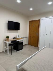 a bedroom with a desk and a tv on the wall at B&B Milicia in Misterbianco