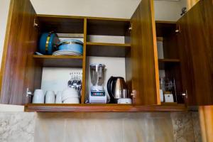 a cupboard with cups and dishes in it at Dodoma Central Apartments in Dodoma +8 photos