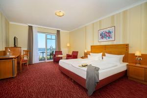 ein Hotelzimmer mit einem großen Bett und einem Schreibtisch in der Unterkunft Strandhotel Prinz von Preussen in Zinnowitz + 37 Fotos