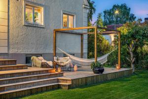 eine Holzterrasse mit einer Hängematte auf einem Haus in der Unterkunft Family-Friendly Retreat Near beach, Malmö & Lund in Åkarp