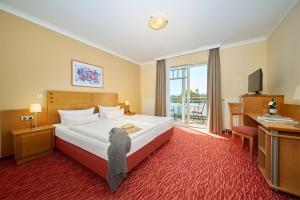 ein Hotelzimmer mit einem Bett, einem Schreibtisch und einem Fernseher in der Unterkunft Strandhotel Prinz von Preussen in Zinnowitz