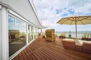 eine Terrasse mit einem Sonnenschirm und Stühlen auf einem Haus in der Unterkunft Strandhotel Prinz von Preussen in Zinnowitz