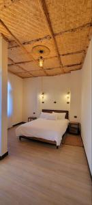 a bedroom with a white bed with a wooden ceiling at Roha Family Gust House in Lalībela