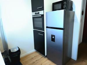 a refrigerator with a microwave on top of it at Appartement Spacieux & Parking in Caen