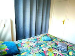 a bed in a bedroom with a blue curtain at Appartement Spacieux & Parking in Caen