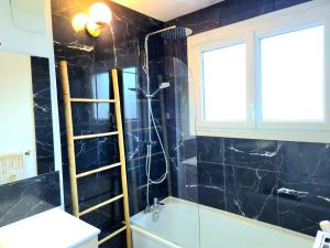 a bathroom with a black tiled wall and a shower at Appartement Spacieux & Parking in Caen +8 photos