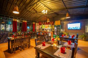 a restaurant with tables and chairs and a television at Parampara Resort & Spa, Coorg in Kushālnagar