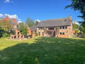 ein großes Backsteinhaus mit großem Hof in der Unterkunft The Threshing Barn - Stunning 5 Bedroom Retreat! in Sedgeberrow