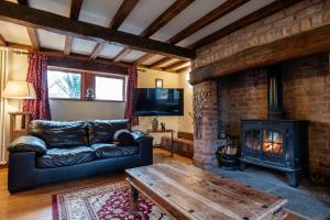 ein Wohnzimmer mit Couch und Kamin in der Unterkunft The Threshing Barn - Stunning 5 Bedroom Retreat! in Sedgeberrow