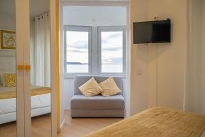 a room with a chair and a window and a television at By the Sea - Nazaré in Nazaré