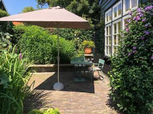 a patio with an umbrella and a table and chairs at t Ateliertje Noort in Bergen