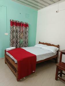 a bedroom with a bed with a red blanket at Bougainvilla in Alleppey
