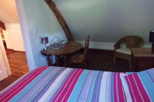 a bedroom with a bed and a table and chairs at B&B - Petite Ferme d'Autrefois in Saint-Georges-Nigremont