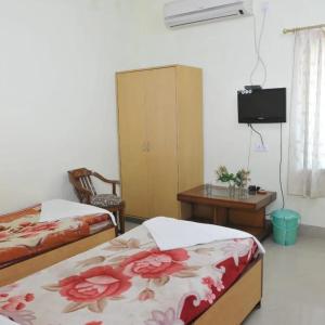 ブッダガヤにあるHotel Kanako Internationalのベッド2台、テーブル、テレビが備わる客室です。