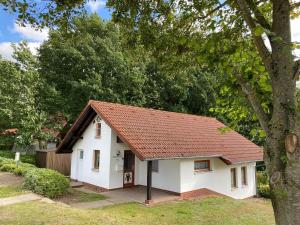ein kleines weißes Haus mit einem roten Dach in der Unterkunft Ferienhäuser am Vogelpark - Boddenhaus 60 in Marlow