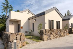 a white house with a stone wall in front of it at 32평자쿠지독채 지금애월 in Jeju
