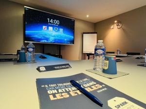 a desk with a book and two bottles of water at Kyriad Toulouse Sud - Roques in Roques Sur Garonne